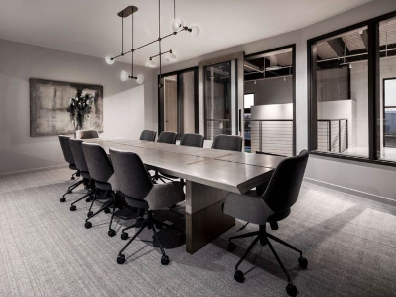  Phòng họp văn phòng hiện đại với thảm và vách tiêu âm, bàn họp dài, đèn chùm thiết kế tối giản.